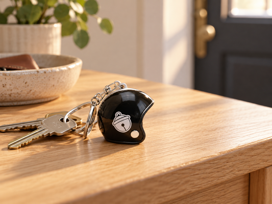 Porte-clés Casque Noisette noir miniature avec anneau et mousqueton posé sur un meuble d’entrée en bois