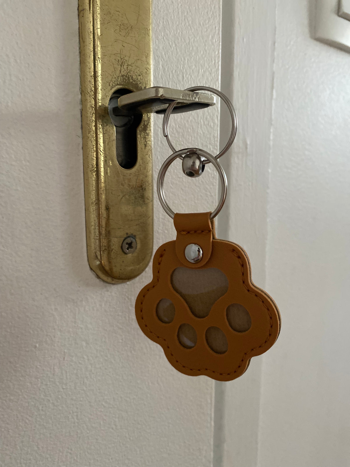 Porte-clés en forme de patte marron accroché à une clé dans une serrure de porte